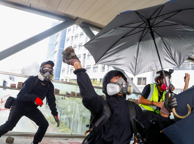 A demonstrator throws a rock on a footbridge during an anti-government protest near City University in Kowloon Tong, Hong Kong, China Nov. 12, 2019. (Thomas Peter/Reuters)