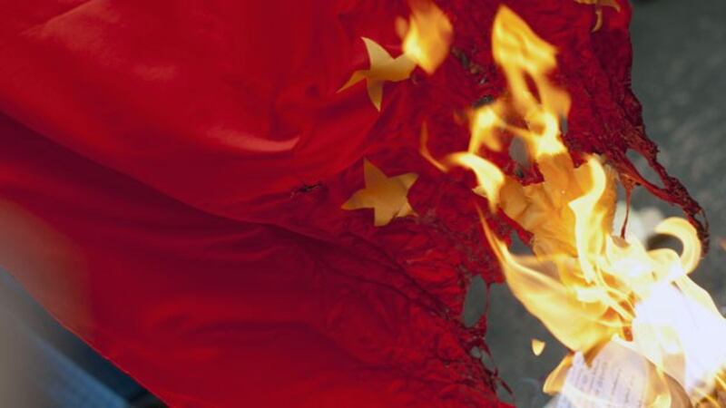 Myanmar activists burn a Chinese flag during a protest against Chinese copper mine company Wanbao in front of the Chinese Embassy in Yangon in a file photo. Wanbao runs the Letpadaung copper mine project in Sagaing region as part of a joint venture with a major Myanmar military conglomerate. 