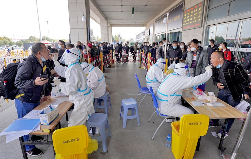 Health workers conduct Covid-19 coronavirus tests on travelers at the exit of Yantai Railway Station in China's eastern Shandong province, Nov. 2, 2021. Credit: AFP