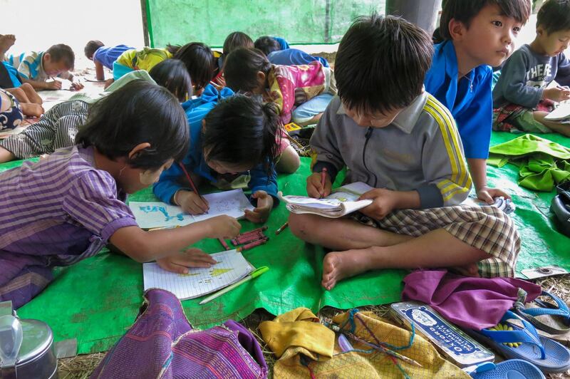 Children displaced by fighting between the military and members of the People's Defense Force attend a school lesson under a makeshift structure as they take refuge in the jungle near Demoso, Kayah state, July 3, 2021. AFP