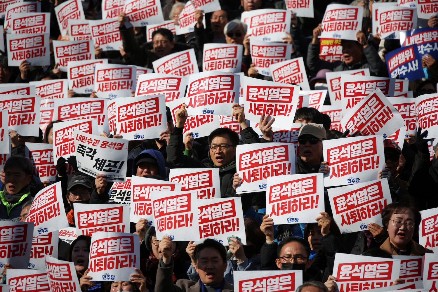 Protesters hold up signs that read “Step down President Yoon Suk Yeol” as people and lawmakers attend a rally to condemn South Korean President’s surprise declarations of the martial law last night and to call for his resignation, at the national assembly in Seoul, South Korea, Dec. 4, 2024.