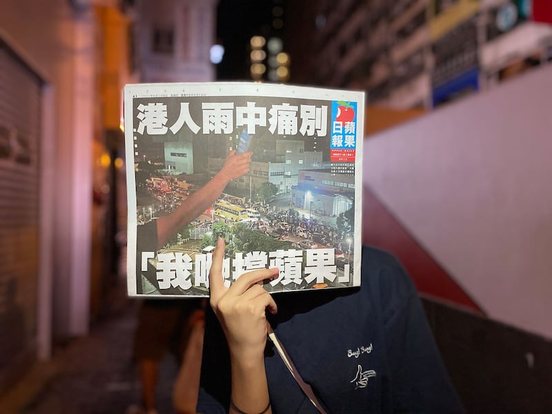 香港市民手举最后一期《苹果日报》。（RFA）