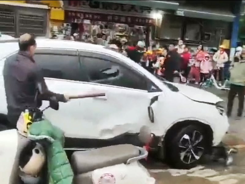 A man breaks a car's window following a vehicle collision outside a primary school in Changde, Hunan province, China. Nov. 11, 2024.