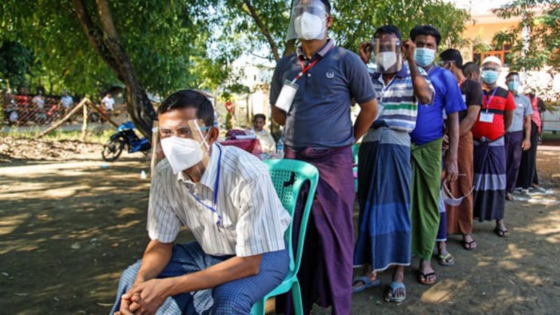 Myanmar voters wearing face shields and face masks to prevent the spread of the coronavirus line up at a polling station in Rakhine state, Nov. 8, 2020.