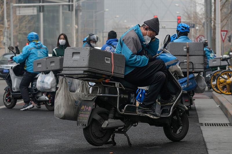 2023年3月20，外卖骑手在北京市一家超市外面等待订单。（美联社）