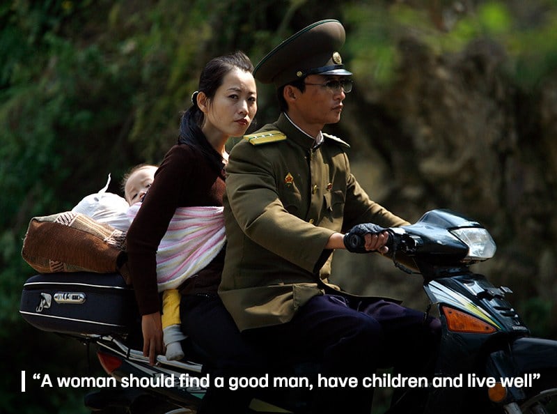 A woman carrying a baby on her back rides on a motorbike with a North Korean soldier along the banks of the Yalu River near the North Korean town of Qing Cheng, located around 50 kilometres north of the Chinese border city of Dandong September 12, 2008.