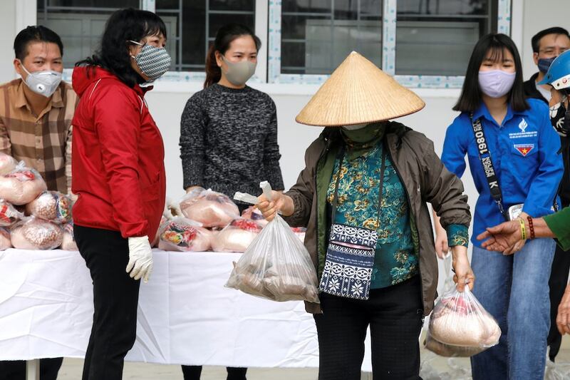 Hình minh hoạ. Một phụ nữ đeo khẩu trang nhận thực phẩm trợ giúp cho người nghèo trong dịch bệnh COVID-19 ở Hà Nội hôm 7/4/2020 