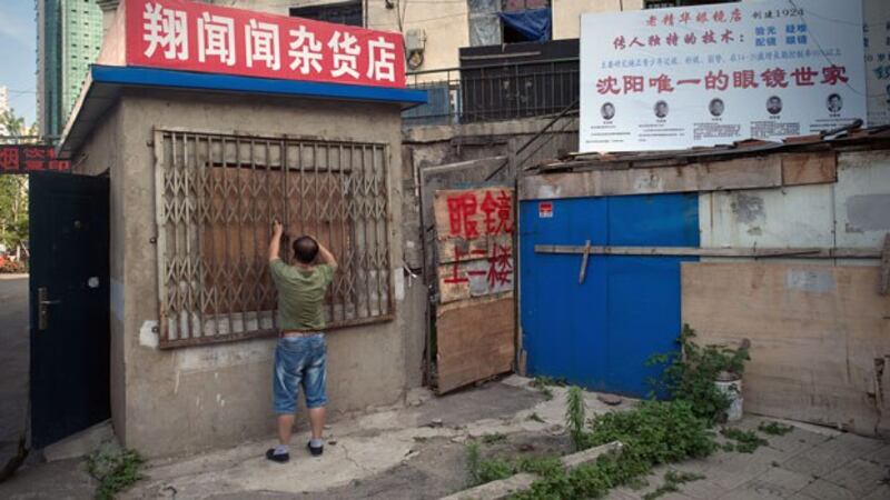 A Chinese man closes his small shop in Shenyang, northeastern China's Liaoning province, July 4, 2017.