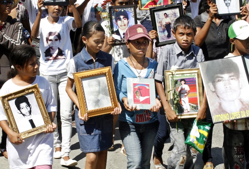 Children hold photos some of the pro-independence demonstrators killed by Indonesian troops in 1991, at the Santa Cruz cemetery, during a commemoration in Dili, East Timor, Nov. 12, 2010.