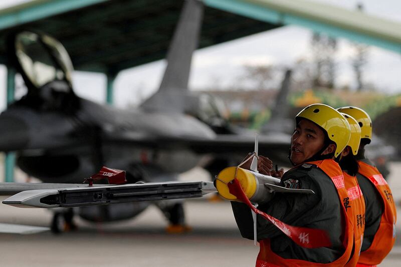 2018 年 1 月 30 日，在台湾军事基地演习中，空军机组人员举起AIM-9响尾蛇空对空飞弹，将其装载到战斗机上。（路透社）