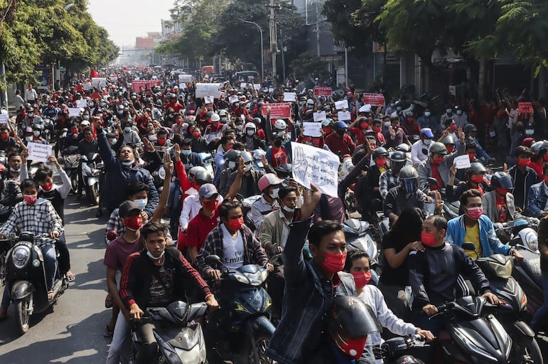 Protesters hold posters during a motorcycle rally demonstration against the military coup near the royal palace in Mandalay, Feb. 7, 2021. Credit: AFP