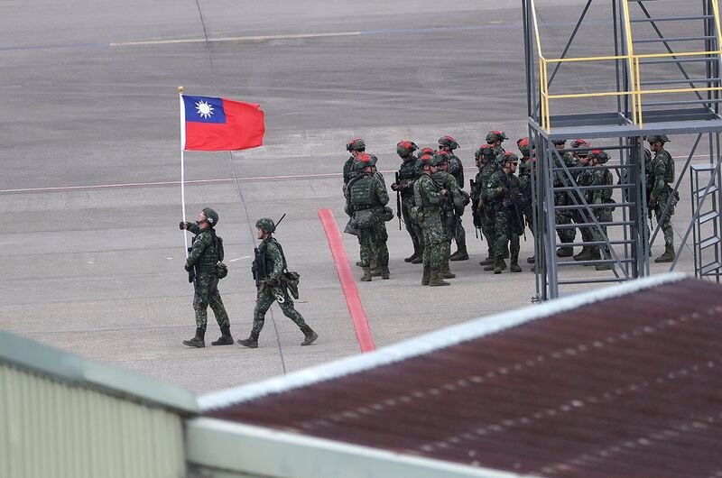 2023 年7 月26 日，台湾年度汉光军事演习中，一名士兵举着台湾旗帜，模拟对台湾北部桃园国际机场机场的袭击。（美联社）