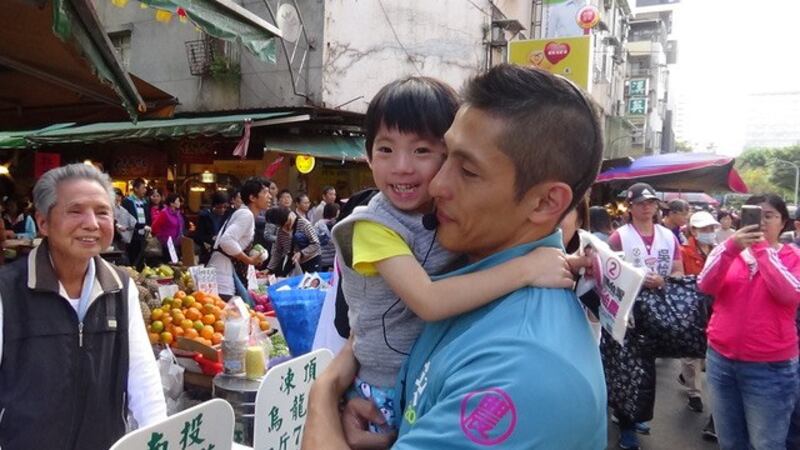 民进党立委候选人吴怡农市场拜票，男女老少通吃。(记者 夏小华摄)