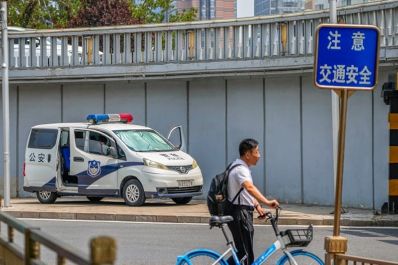 A man pushes a bicycle past by a police van stationed at a bridge along Chang'an Avenue in Beijing, China, June 4, 2024. (Andy Wong/AP)