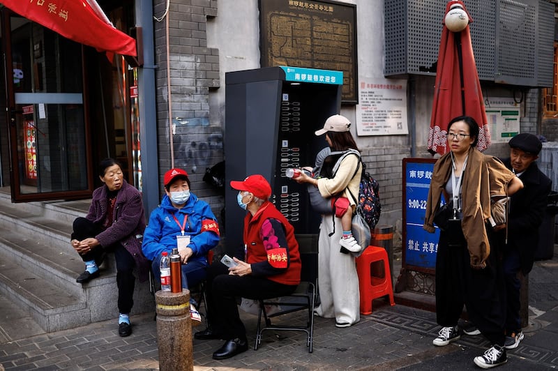 Community workers wearing armbands sit by a street as the Third Belt and Road Forum is held in Beijing, Tuesday, Oct. 17, 2023. Credit: Tingshu Wang/Reuters