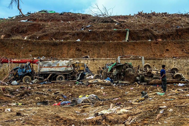 A man stands amongst debris in the aftermath of a military strike on a camp for displaced people near northern Laiza area on Oct. 11, 2023. Credit: AFP