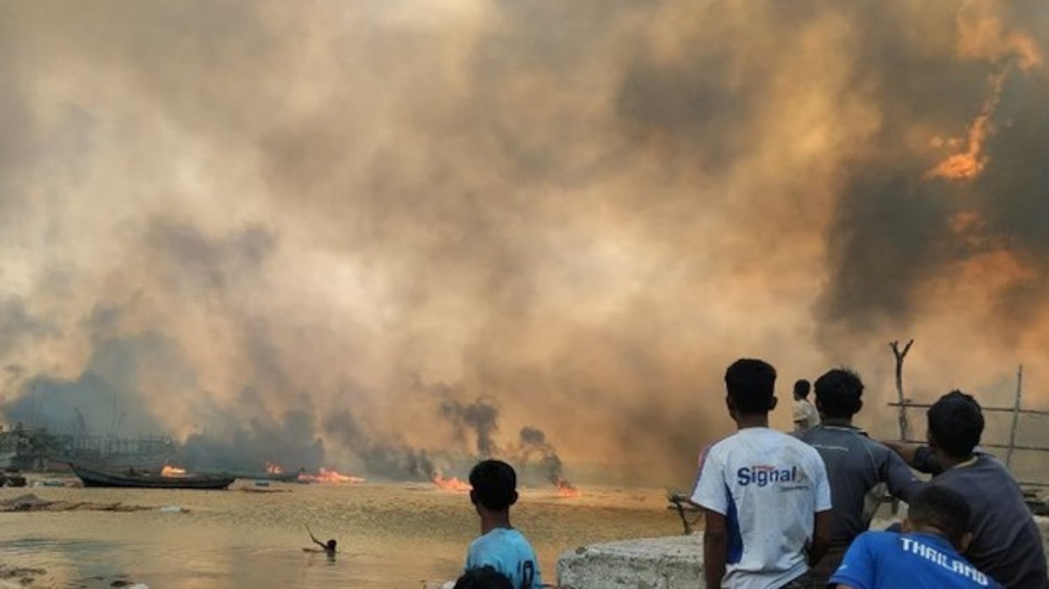 Villagers watch homes burning in Kyauk Ni Maw village, in Rakhine state, after a raid by the Myanmar air force on Jan. 8, 2025.