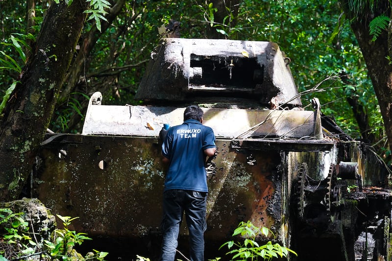 A member of the clearance team from the mine action group Norwegian People’s Aid peers into an American tank abandoned after WWII in Peleliu, Palau, Nov. 26, 2024.