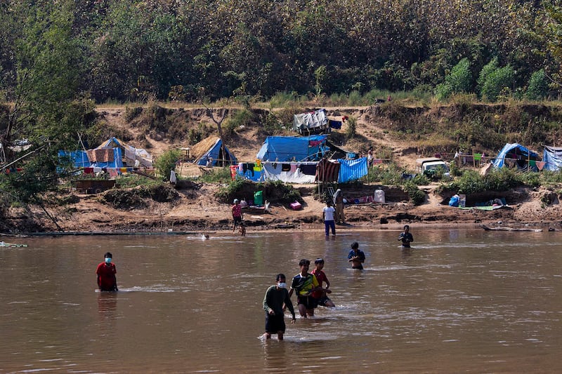 Myanmar refugees walk across the river to enter Thailand's Mae Sot district, Jan. 15, 2022. Credit: AFP