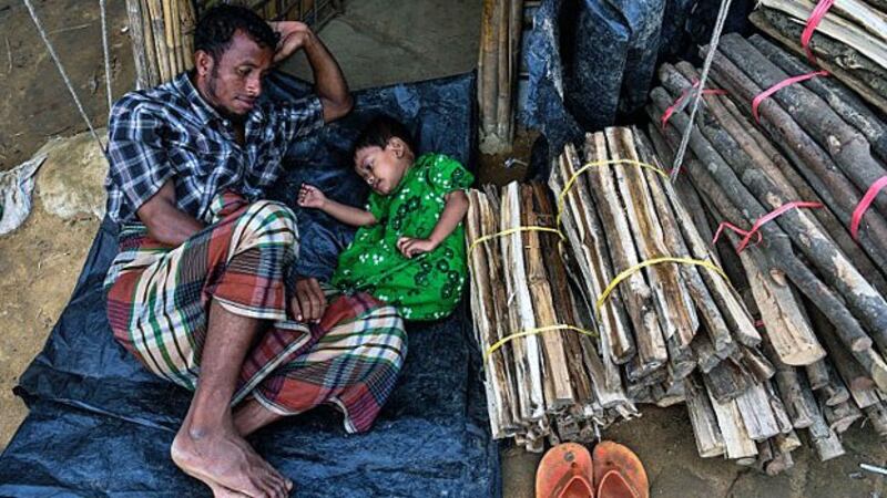 A Rohingya refugee man from Myanmar plays with his daughter by the entrance of their tent at the Kutupalong camp in Ukhia sub-district, Cox's Bazar, in southeastern Bangladesh, Aug. 13, 2018.