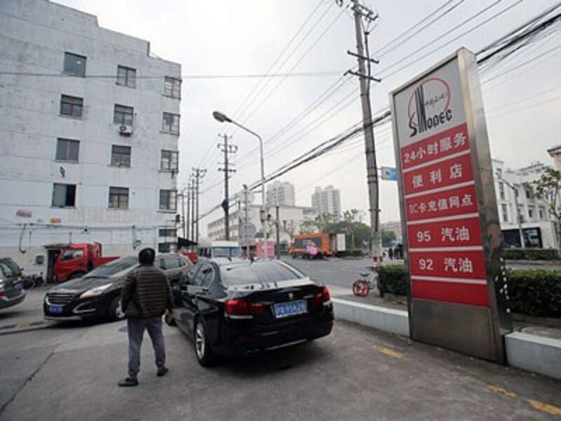 A Chinese driver stands beside his car at a gas station operated by Sinopec, as the China Petroleum and Chemical Corporation is also known, in Shanghai, Nov. 30, 2016.