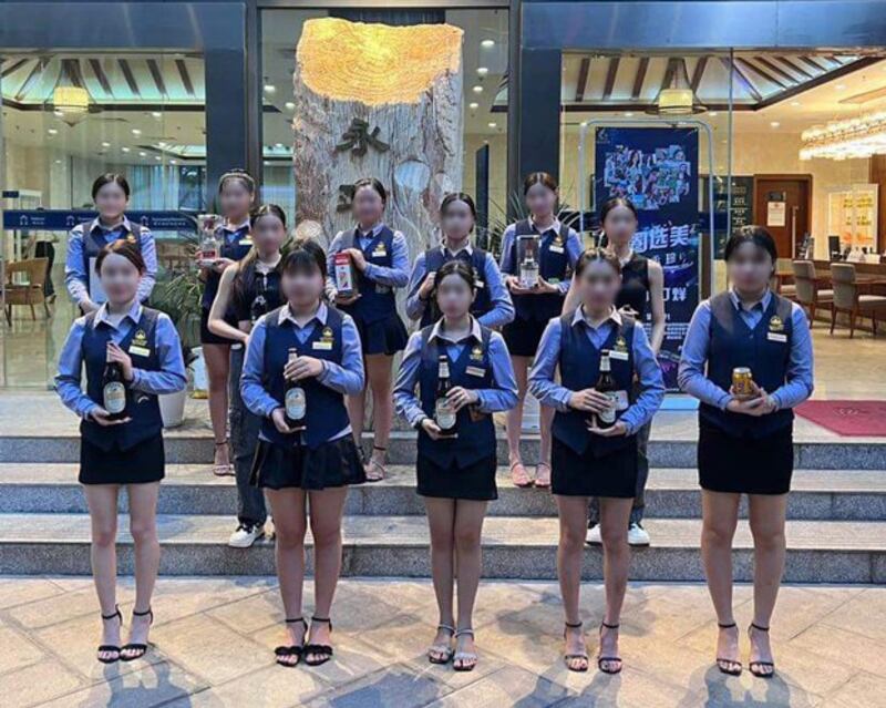 Employees at the Vientiane Mekong Hotel in Vientiane, Laos, hold bottles of wine and beer that Chinese patrons can win by throwing a large plastic hoop around the women, Feb. 14, 2024. The women's faces were blurred by RFA to protect their privacy. (Image from Joseph Akaravong video via Facebook)