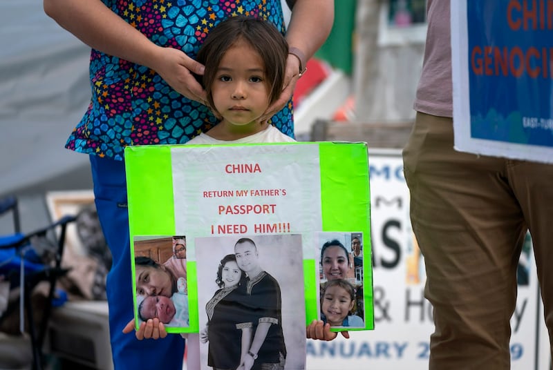 Addlet Sabit comforts her daughter as she displays pictures of her father, Ablimit Ablaze whom she has never met, during a hunger strike in front of the White House in Washington, D.C., Sept. 21, 2022. Credit: Gemunu Amarasinghe/RFA