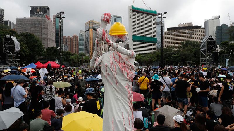 2019年8月18日，香港反送中集会上，展示了民主女神的复制品，戴着安全帽，防毒面具，手铐，并用红色液体覆盖。（美联社） 