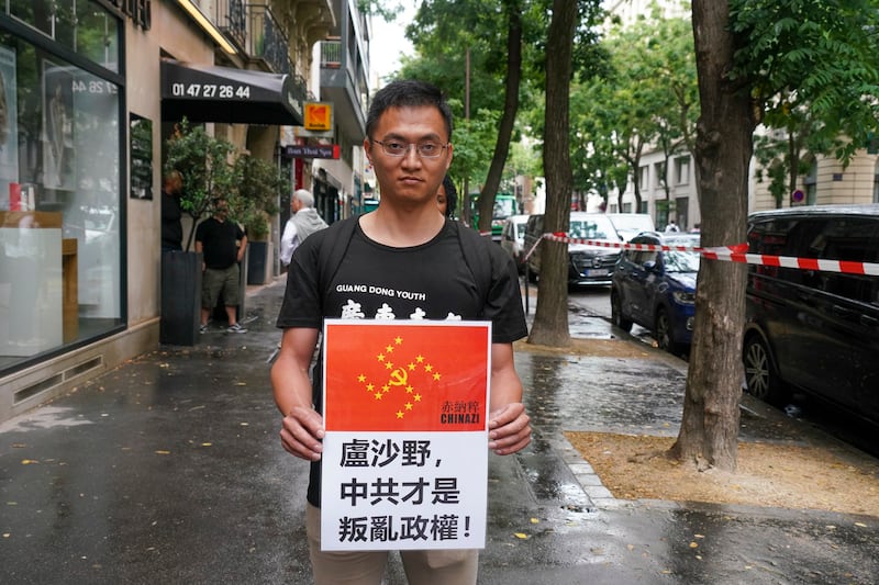 Netherlands-based Chinese rights activist Liu Feilong holds up a placard calling Beijing a "rebel regime" in Paris ahead of the Olympic Games opening ceremony, July 26, 2024. (RFA)