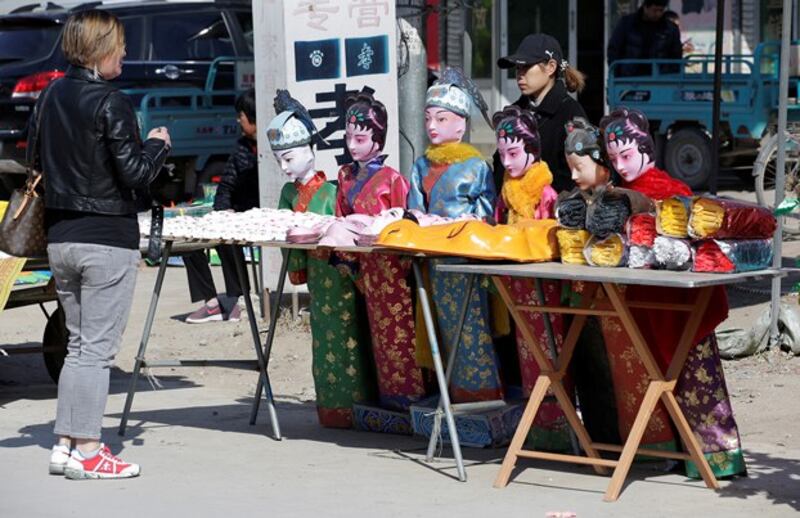 A customer checks prices with a saleswoman next to offerings at a wholesale market where supplies for ceremonial rites for the dead are sold, in Mibeizhuang, Xiong county, in northern China's Hebei province, March 24, 2019, ahead of the Qingming festival. (Jason Lee/Reuters)