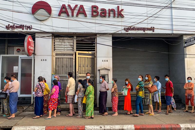 People wait for a branch of the AYA Bank to open in Yangon, April 12, 2021. AFP