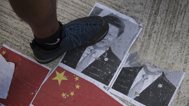 Protesters walk on an image of Chinese President Xi Jinping in the Causeway Bay area in Hong Kong, Oct. 1, 2019. 