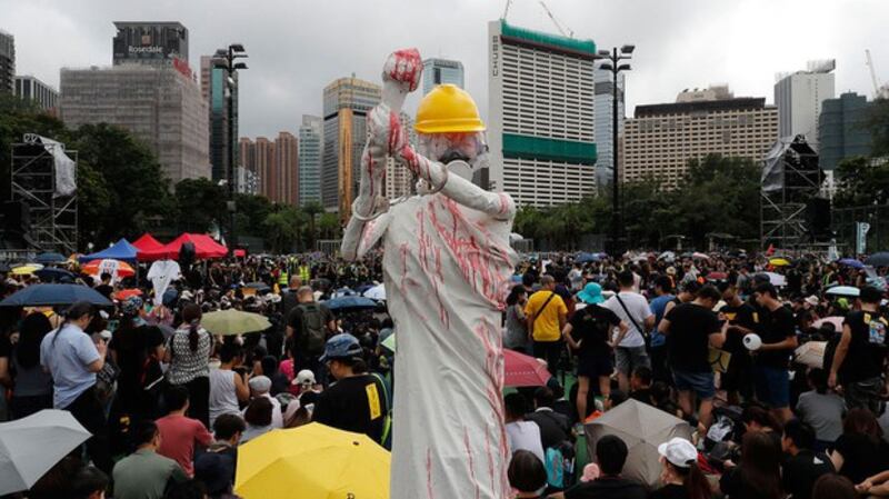 2019年8月18日，香港反送中集会上，展示了民主女神的复制品，戴着安全帽，防毒面具，手铐，并用红色液体覆盖。（美联社）