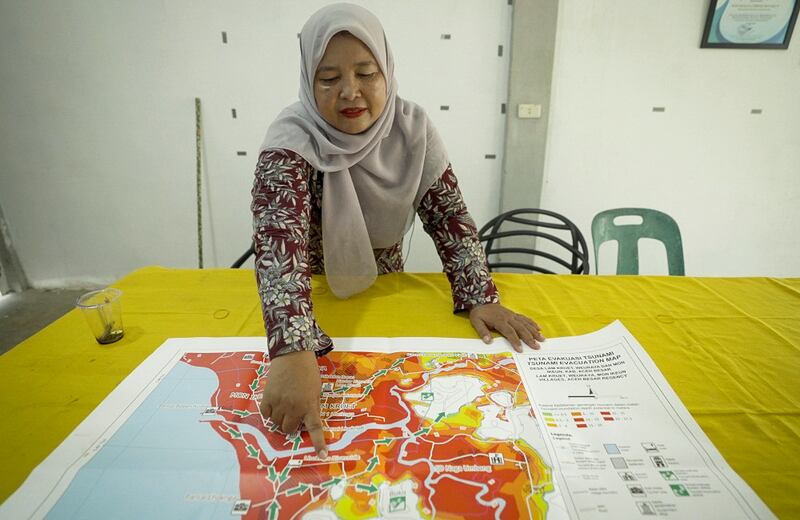 Irma Lisa, the Mon Ikeun village secretary, checks the evacuation map for her village in Aceh province, Indonesia, Dec. 2, 2024.