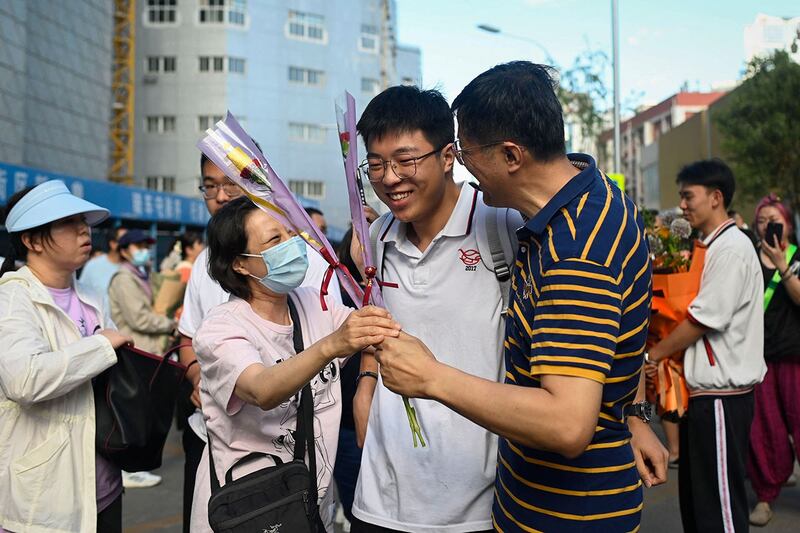 2023年6月10日，北京一名学生在完成高考结束后走出学校时与家人一起庆祝。（法新社）