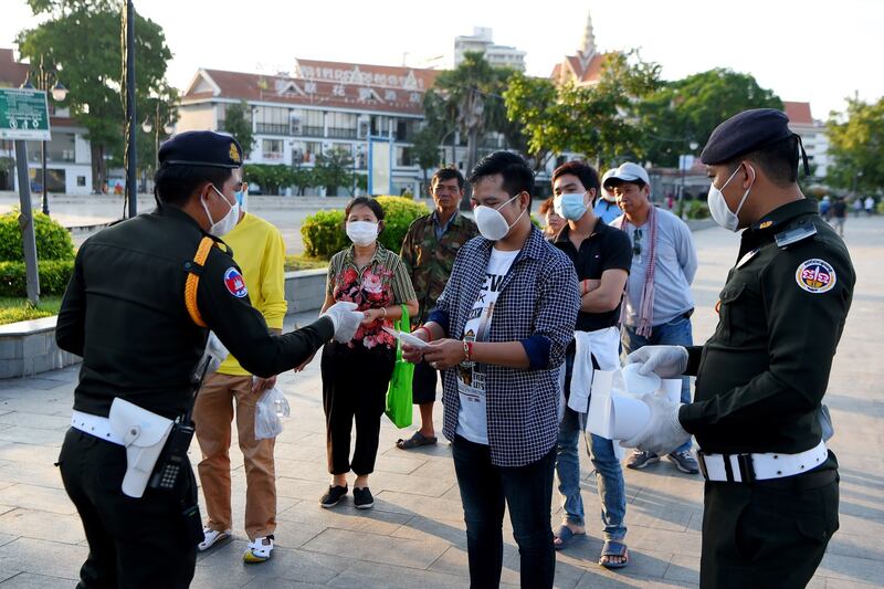 Military police officers hand out free facemasks to people amid concerns over the coronavirus at a park in Phnom Penh, Nov. 12, 2020.