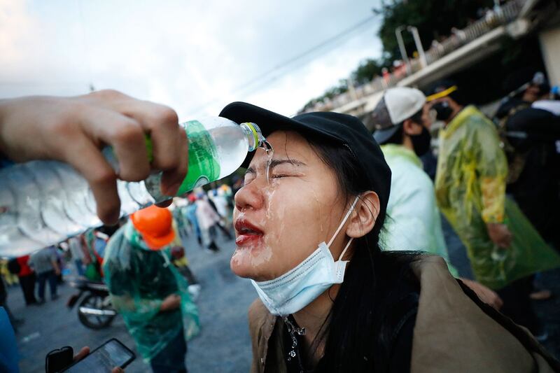 2020 年 11 月 17 日，泰国学运举行集会期间，防暴警察使用催泪瓦斯驱散，抗议者用水冲洗眼睛。 （美联社）