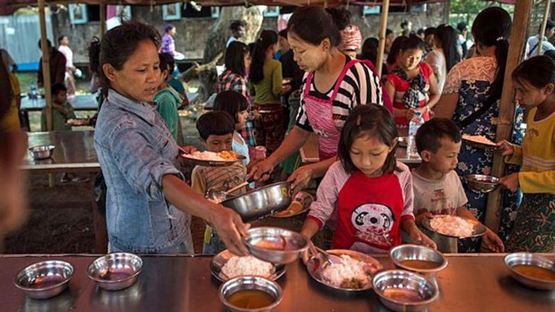 Internally displaced women and children receive food in a temporary shelter at a church compound in Tanghpre village outside Myitkyina, capital of northern Myanmar's Kachin state, May 11, 2018.