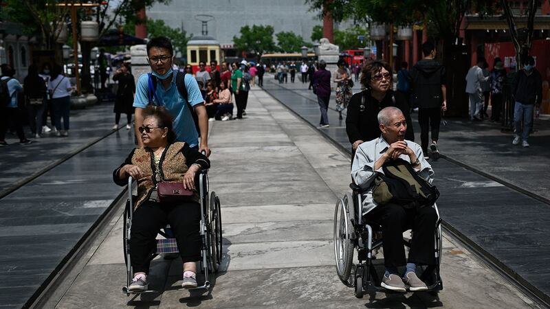 2021年5月11日，在北京的一条街道上，一名老年男女坐着轮椅。 （法新社）