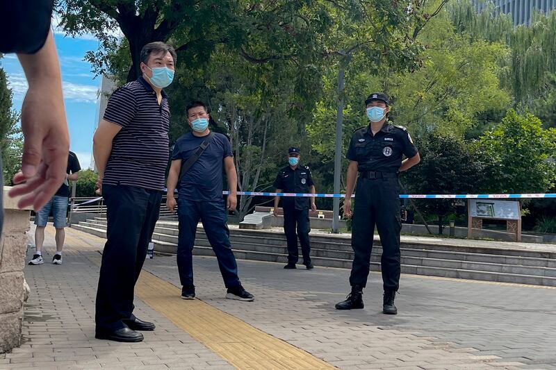 Plainclothes policemen and security guards wearing face masks stand guard as they stop journalists preventing them from getting near the No. 1 Intermediate People's Court, where Zhou Xiaoxuan was filing her appeal case against CCTV host Zhu Jun in Beijing, Aug. 10, 2022. Credit: AP