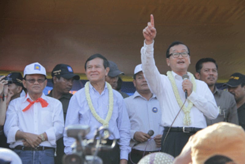 Sam Rainsy (R) raising his hand and Kem Sokha (L) with garland at the rally, Dec. 15, 2013. 