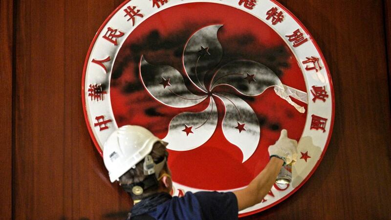 A protester defaces the Hong Kong emblem after protesters broke into the government headquarters in Hong Kong, July 1, 2019