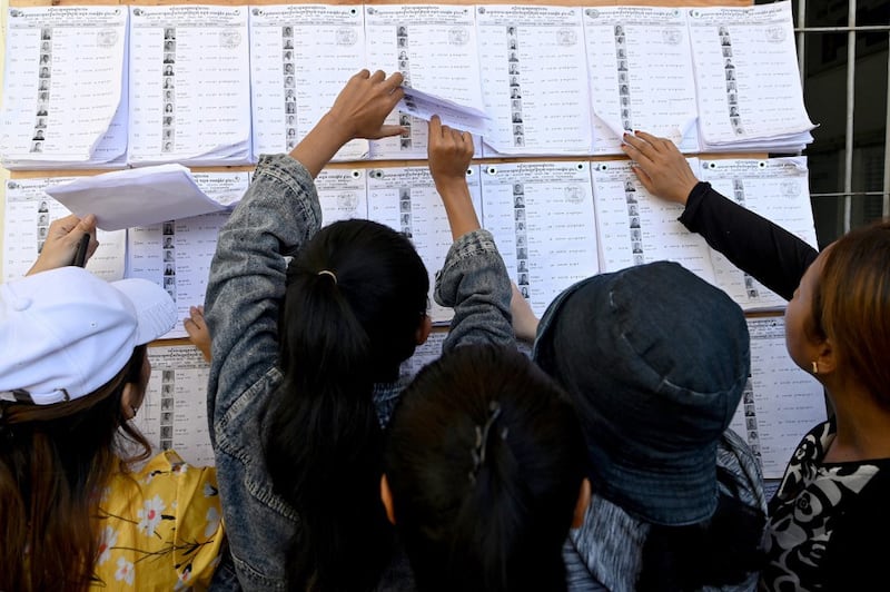 People look for their names in the voters' list at a polling station during local commune elections in Phnom Penh, June 5, 2022. Credit: AFP