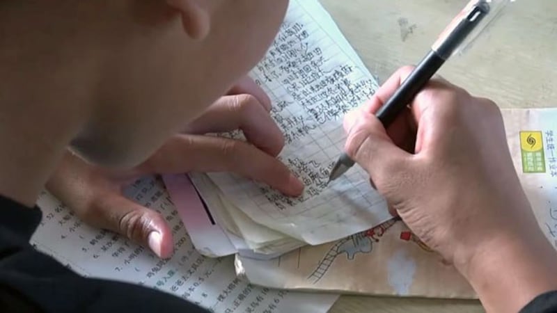 An ethnic Mongla boy writes Chinese characters in a notebook in the Mongla autonomous special region of eastern Myanmar's Shan state, July 2019.