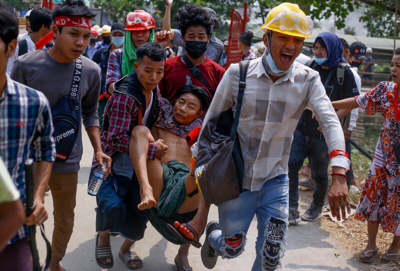 In this March 14, 2021 photo, anti-coup protesters carry an injured man following clashes with security forces in Yangon, Myanmar. (AP Photo)