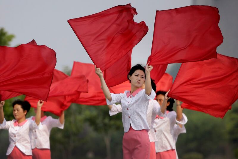 A North Korean cheerleading group wave flags to propaganda music near a road intersection as people start their day early morning on Saturday, June 17, 2017, in Pyongyang, North Korea. (AP Photo/Wong Maye-E)