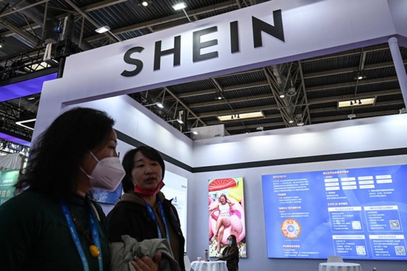 People walk past the booth of fast fashion e-commerce company SHEIN during the China International Supply Chain Expo in Beijing, Dec. 1, 2023. (Jade Gao/AFP)