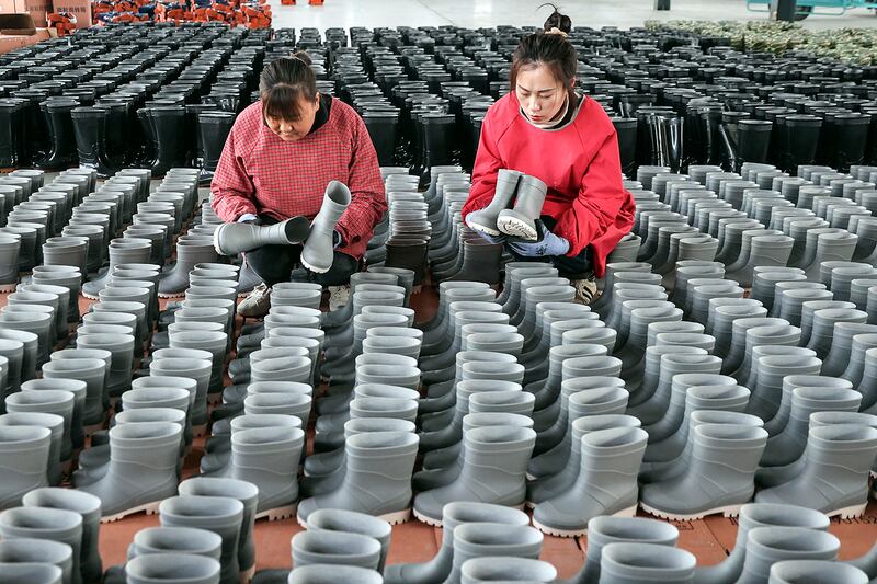 Employees check rain boots for export at a shoe factory in Lianyungang, China, March 13, 2024.