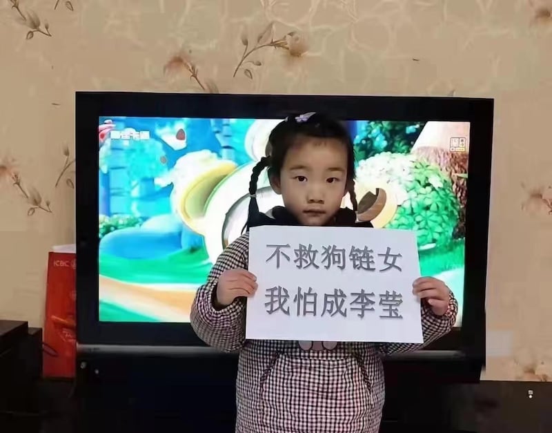 网民上传图片，一名儿童手持写有“不救狗链女，我怕成李莹”的纸牌。（Public Domain）