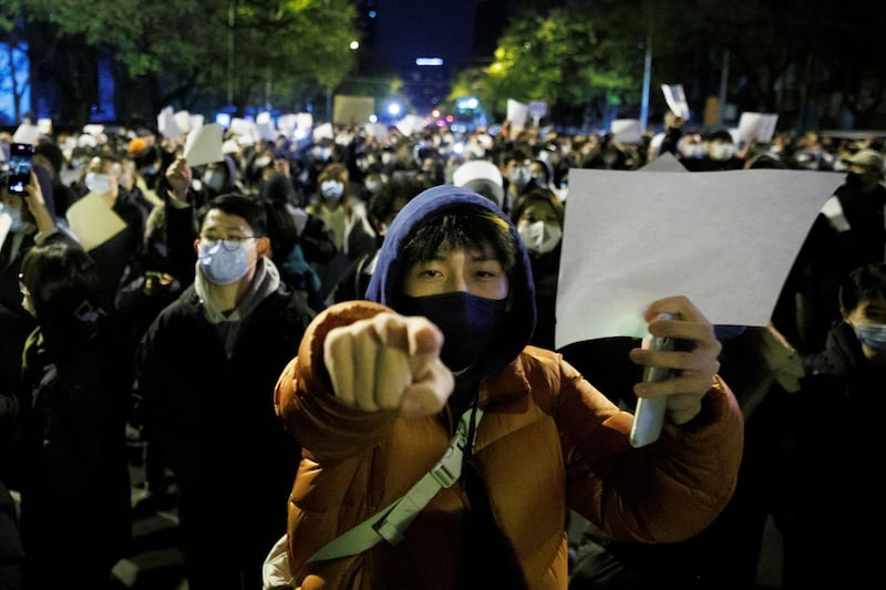 People hold white sheets of paper in protest over coronavirus disease (COVID-19) restrictions, after a vigil for the victims of a fire in Urumqi, as outbreaks of COVID-19 continue, in Beijing, China, November 27, 2022. REUTERS/Thomas Peter